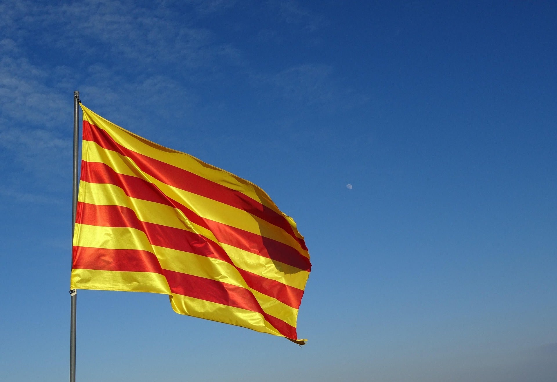 🟥🟨 La senyera catalana onejant al vent sota un cel clar i blau.
