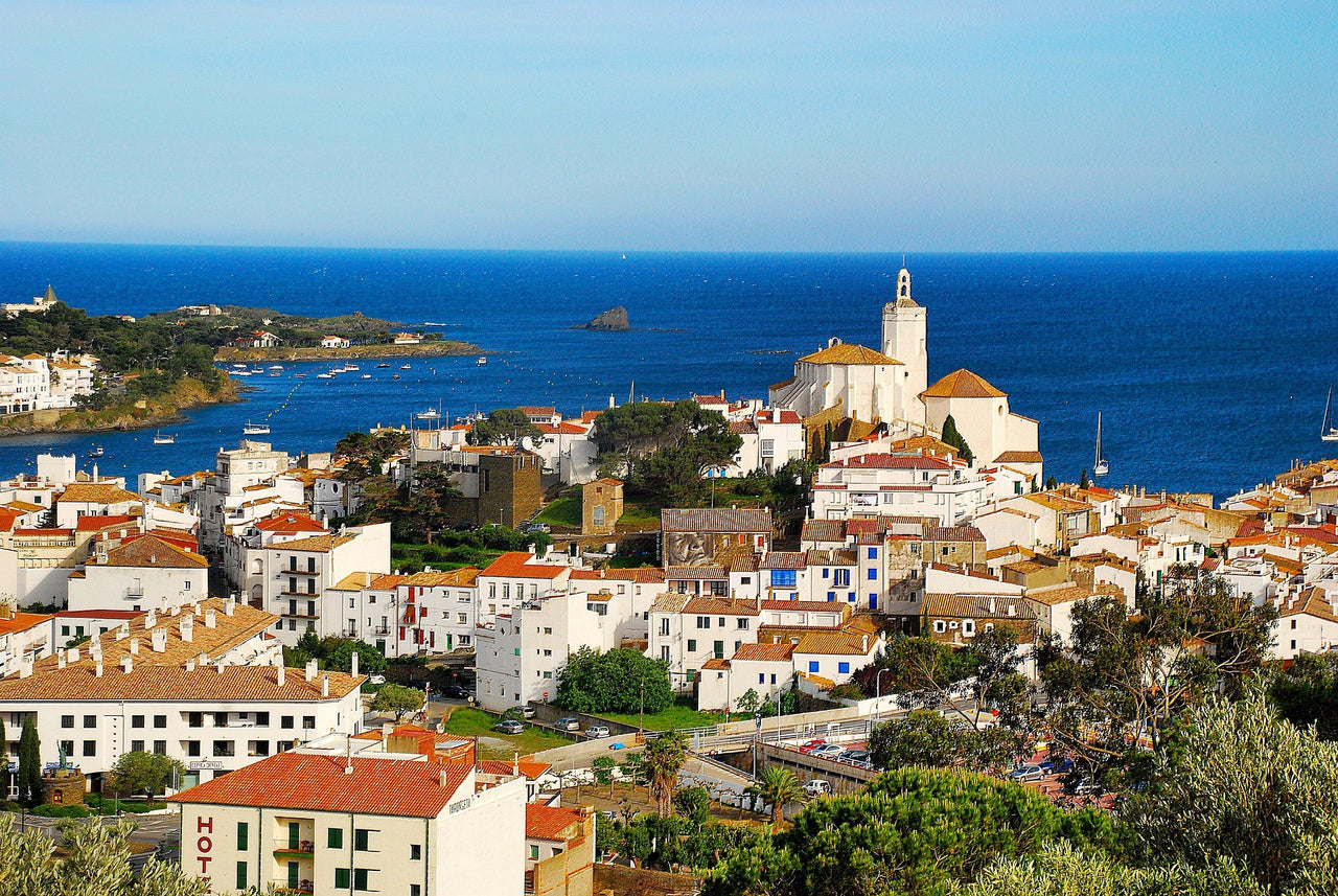 🏖️ Cadaqués, un poble costaner de la Costa Brava amb teulades vermelles i església blanca davant del mar.