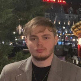 Kyle Cross, Swish & Click’s Commercial & Support team member, standing outdoors at night near a lit-up structure in Amsterdam — focused on supplier partnerships and backend operations across Europe.