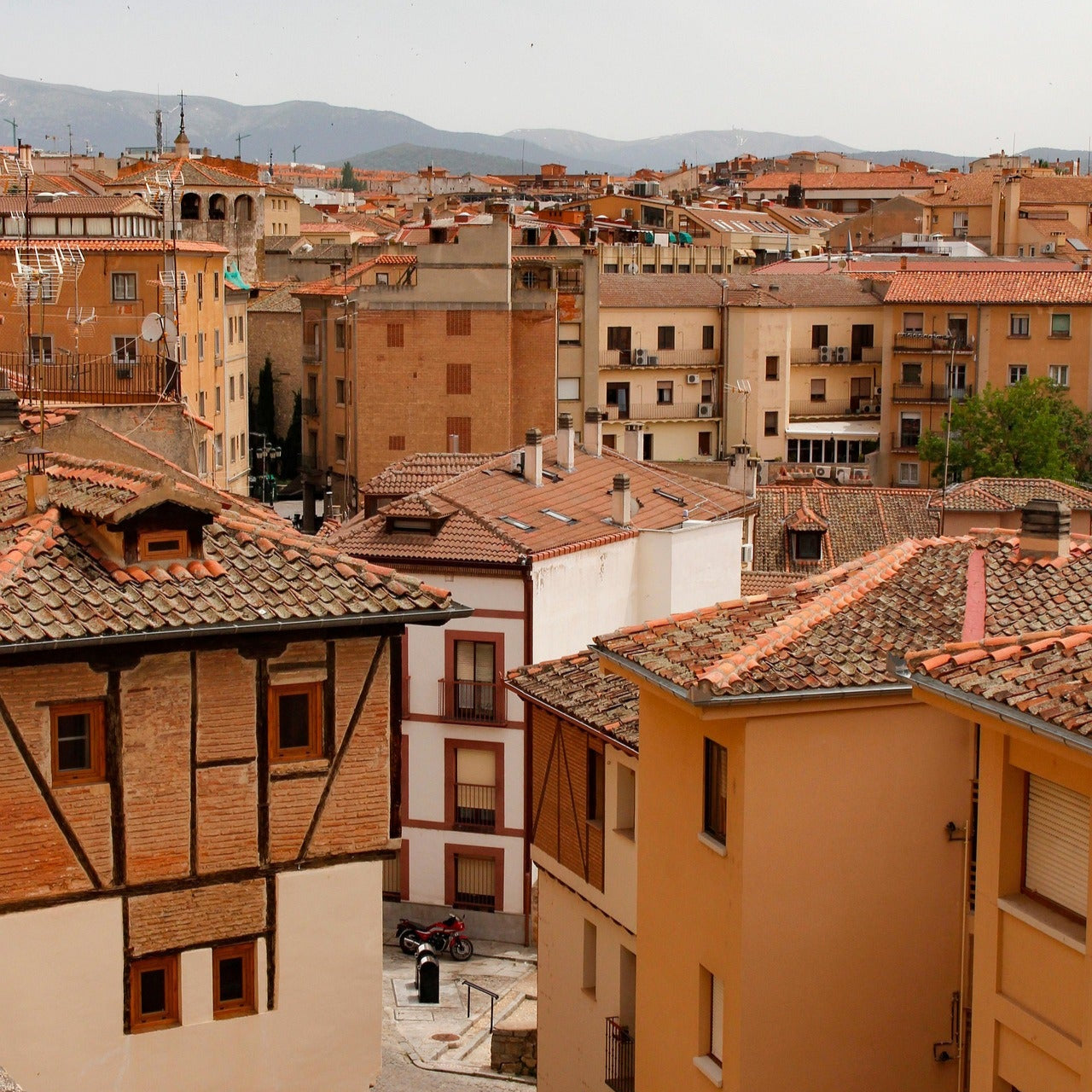🟤 Vista dels terrats i edificis històrics de Segòvia, amb les muntanyes de fons en un dia assolellat.